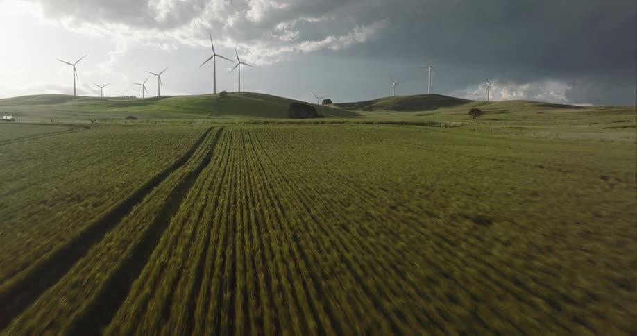 Aerial of wind turbines on a hill in the distance in the country