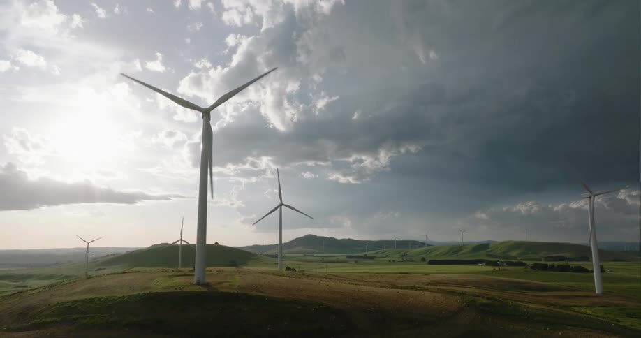 Wind turbines rotate slowly under heavily clouded sky on misty day