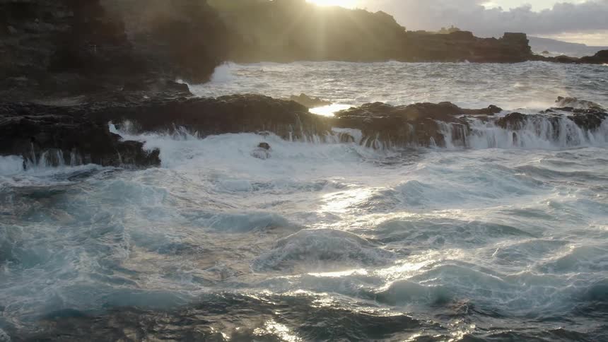 Aerial view of waves crashing on the rocks in the coast near the mountains at morning