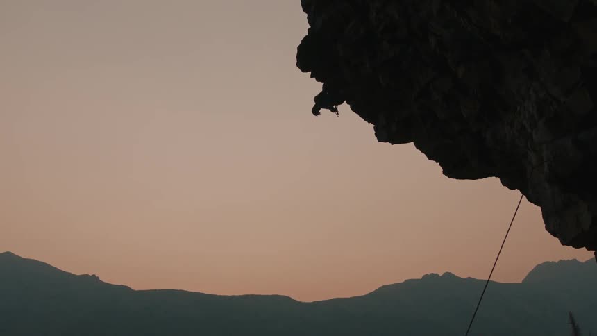 Silhouette of a cliff and a mountain climber on the edge