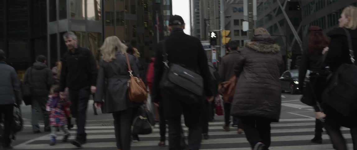 People are walking across the street in a city