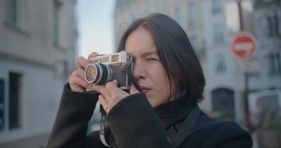 A woman takes a photograph in the city