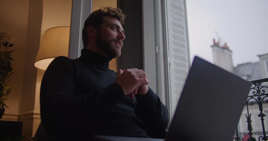 A man sitting on a balcony on a laptop