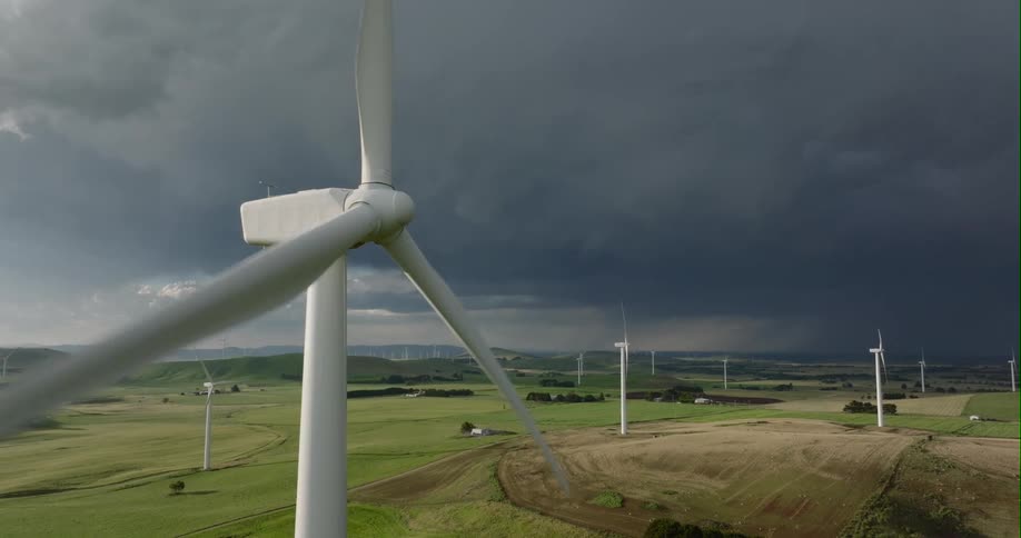 Wind turbine spinning on a wind farm in the fields close to storm clouds