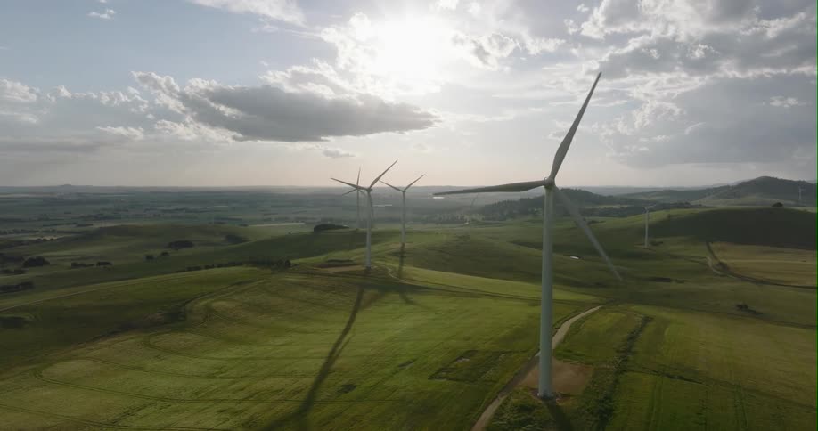 Wind turbines spinning on a wind farm in the hills on the grassland at morning