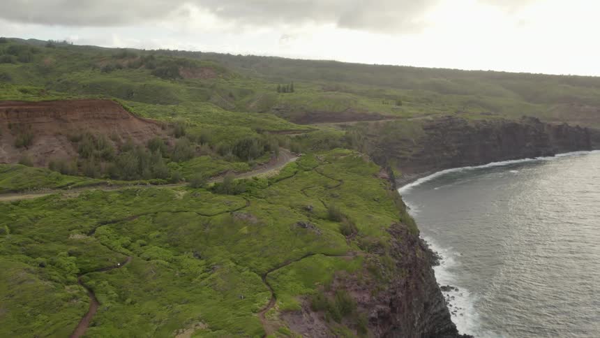 A grass covered river bank and flowing river under a cloudy sky