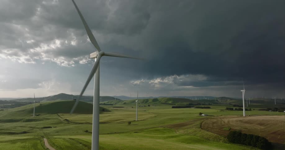 Wind turbine blades turn slowly against stormy sky