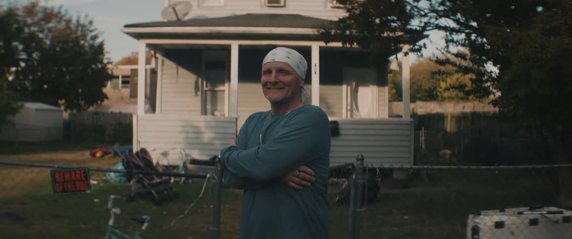Happy smiling man standing in front of a house in the neighborhood at evening