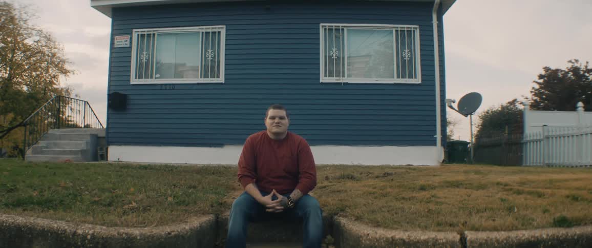 A man sitting on steps in front of a house in a neighborhood