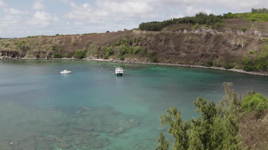 Two boats are anchored near the island shore