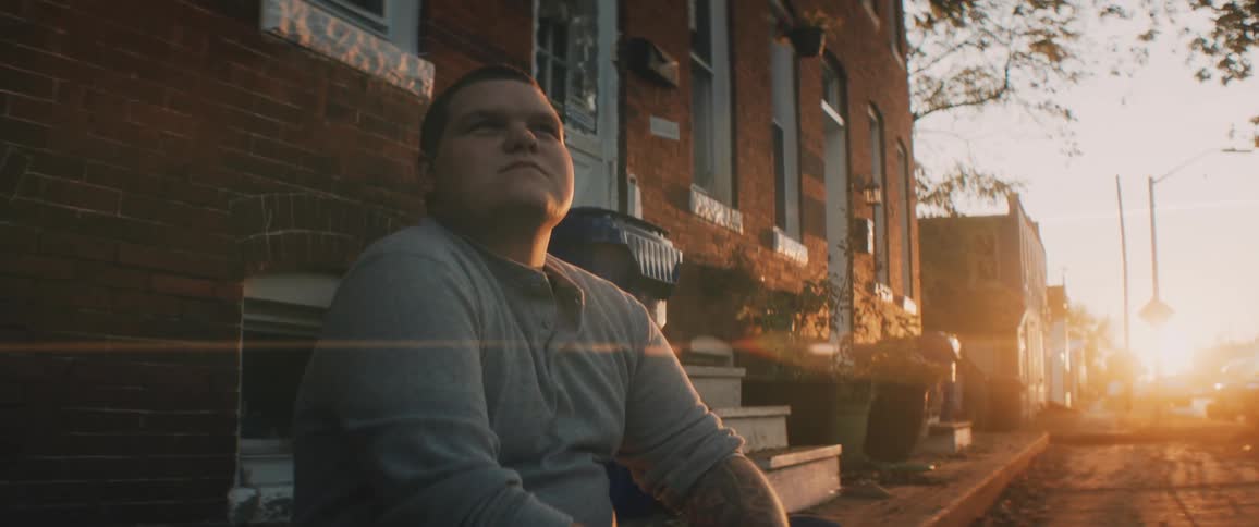 A man sits outside his home watching the sun rise