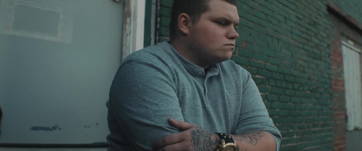 A man is sitting outside his home