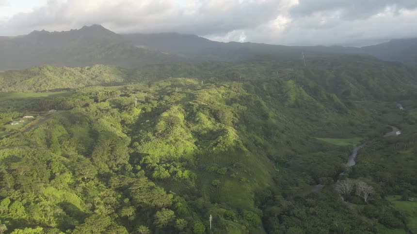 Aerial view of river valley between green mountains on cloudy day