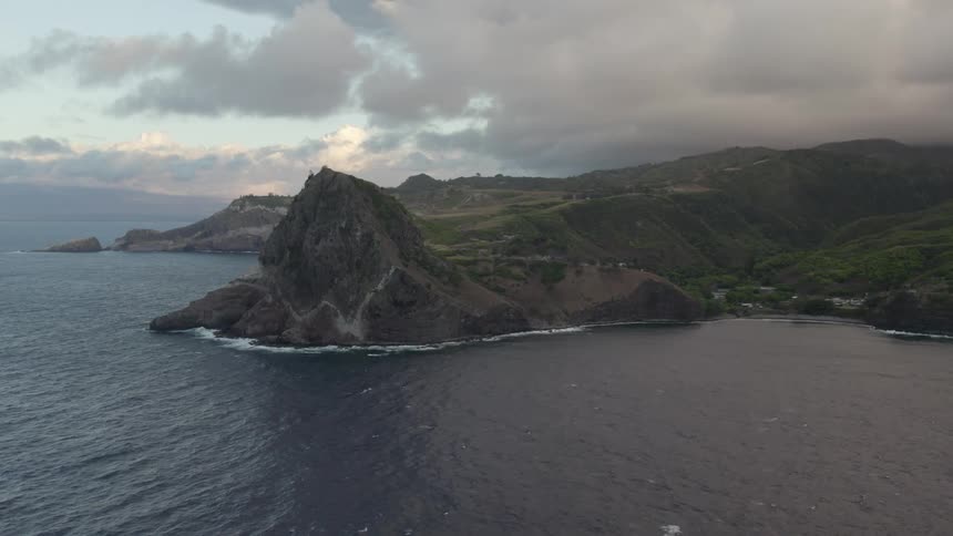 Storm front slowly moves across mountains leading to shore as waves roll across ocean