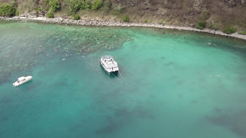 Yacht and a boat near the coast of a beach on the clear blue water
