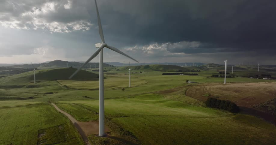 Wind turbine spinning on a wind farm in the hills close to storm clouds