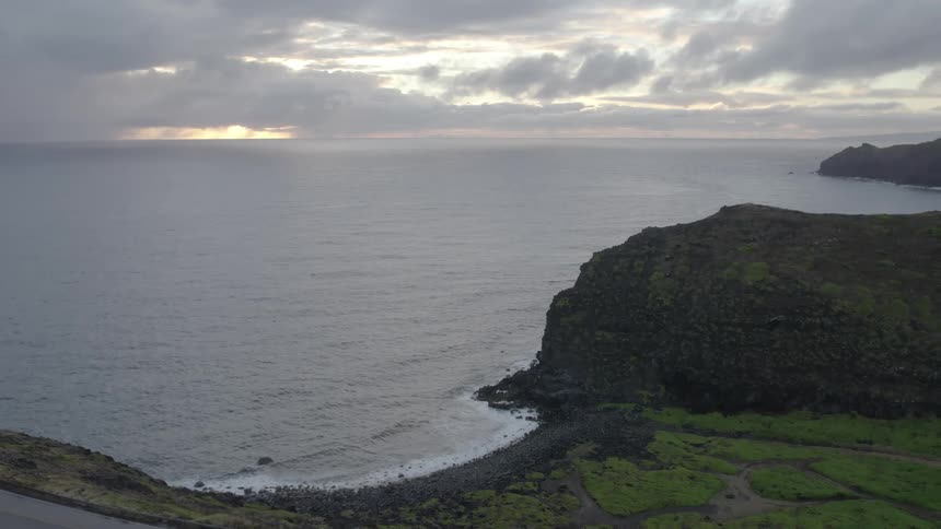 Aerial view of a small beach on the coast next to the ocean at sunset