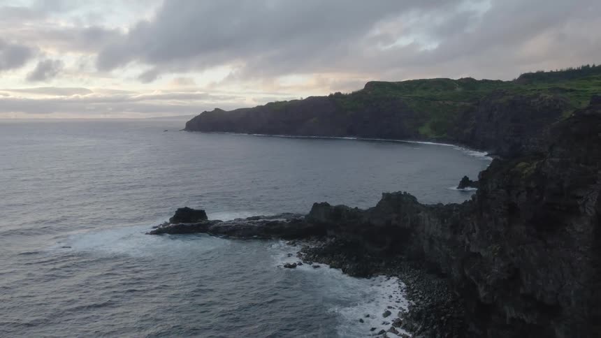 The waves are crashing against the island cliff