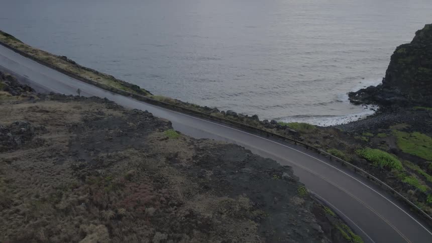 Ocean stretches from highway hugged coast to clouds on the horizon