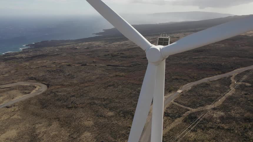 The windmills are lined up on the hills by the water