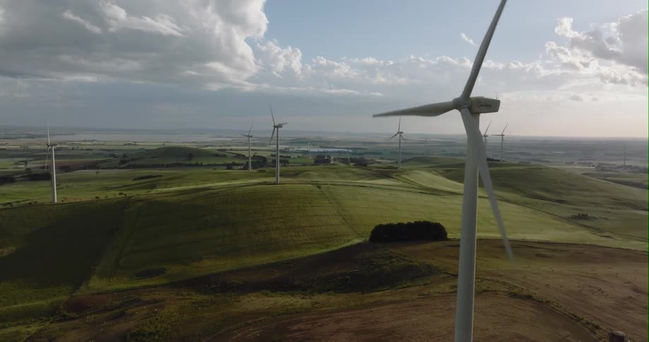 Wind turbines in wind farm turning slowly against pink tinted hazy horizon