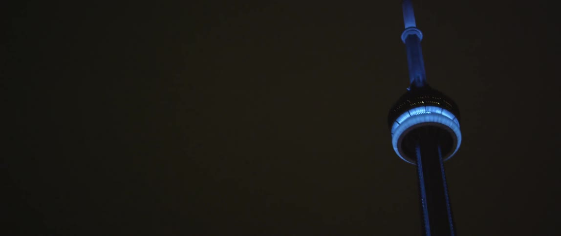A tall tower has blue lights in a night sky