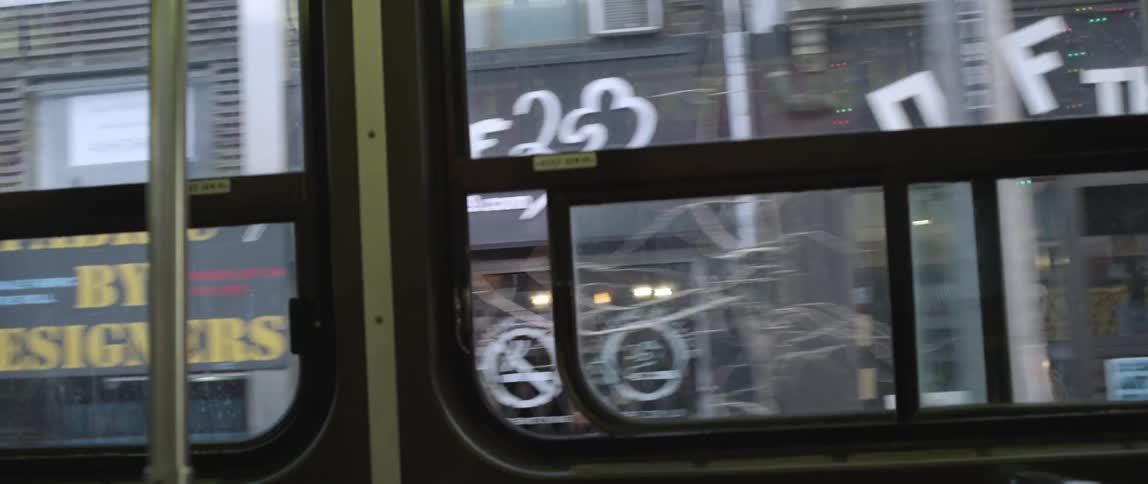 A bus is driving down a street passing shops