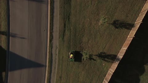 Someone riding a lawnmower next to a road