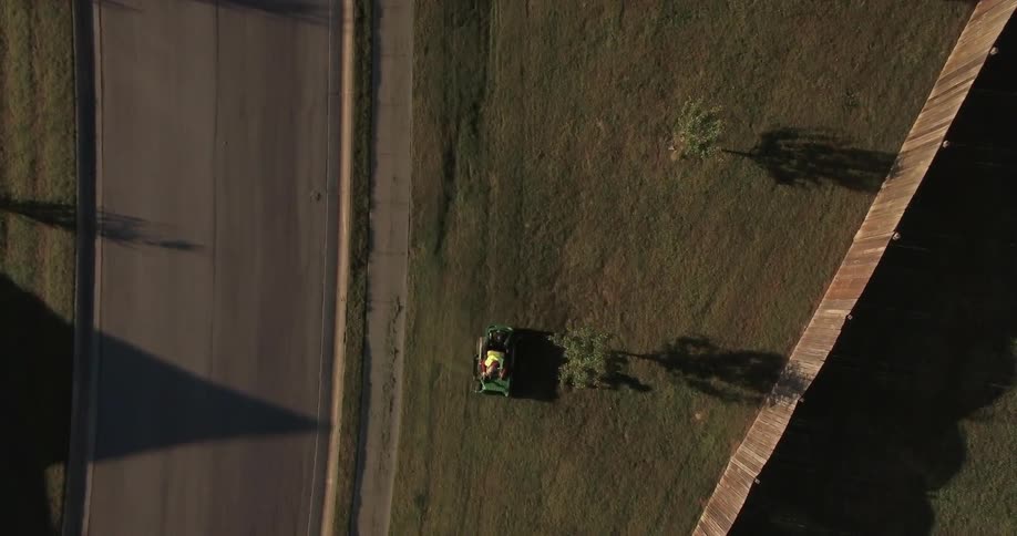 Someone riding a lawnmower next to a road