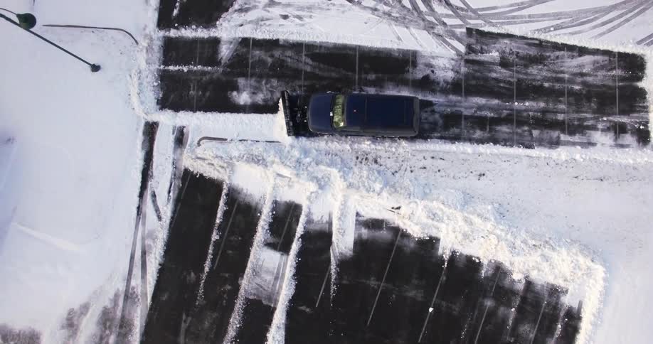 Aerial view of a snow plow in a parking lot