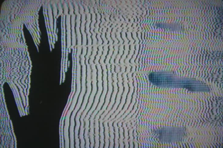 Black silhouette of a hand on a television screen with moving static lines