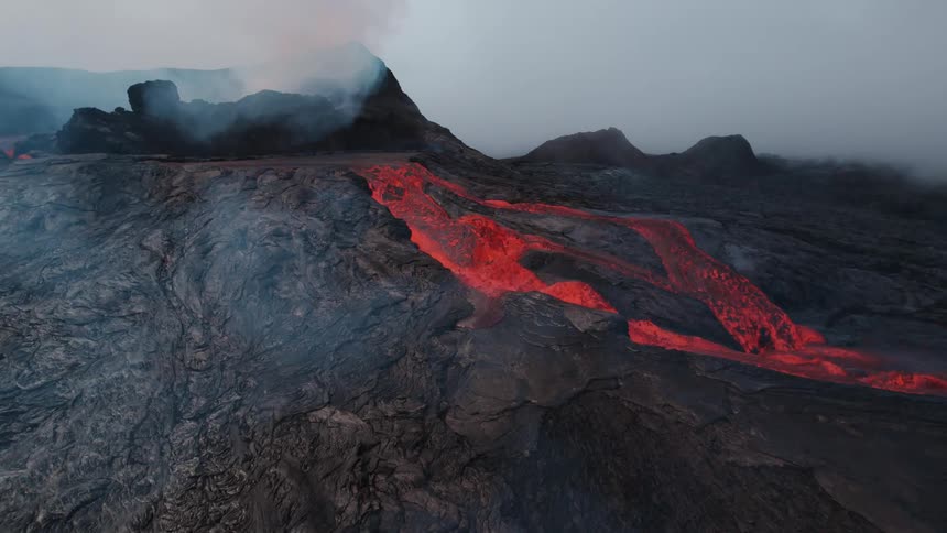 Smoke fills the air as lava flows from a volcano