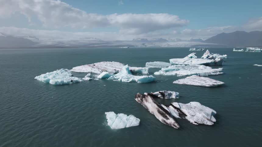 Chunks of ice are floating in ocean water in the arctic on a sunny day