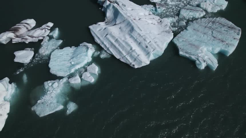 Aerial view of glacier fragments in sea next to coastal town