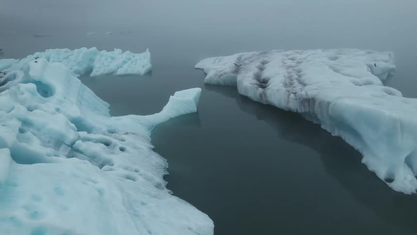 An aerial view of icebergs floating out in the ocean