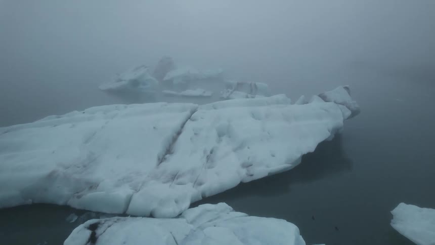 Aerial view of icebergs floating on the arctic ocean under the fog
