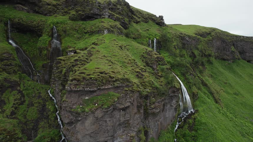 Multiple streams and waterfalls run down the side of a canyon