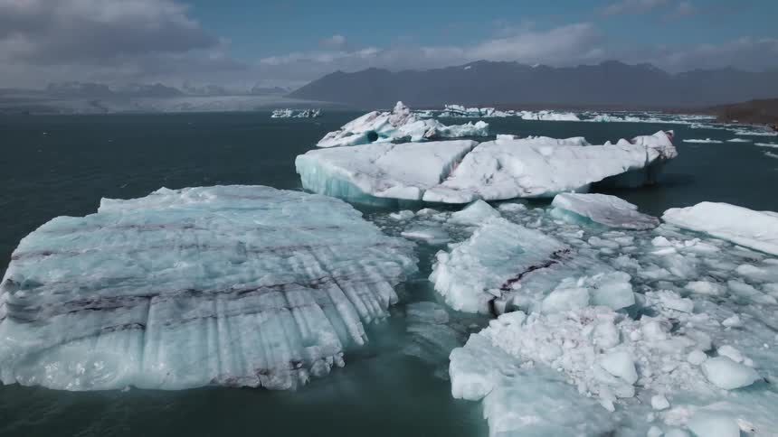 Aerial view of icebergs floating over the ocean close to the mountains