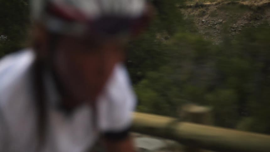 A woman bikes across a bridge with a river below