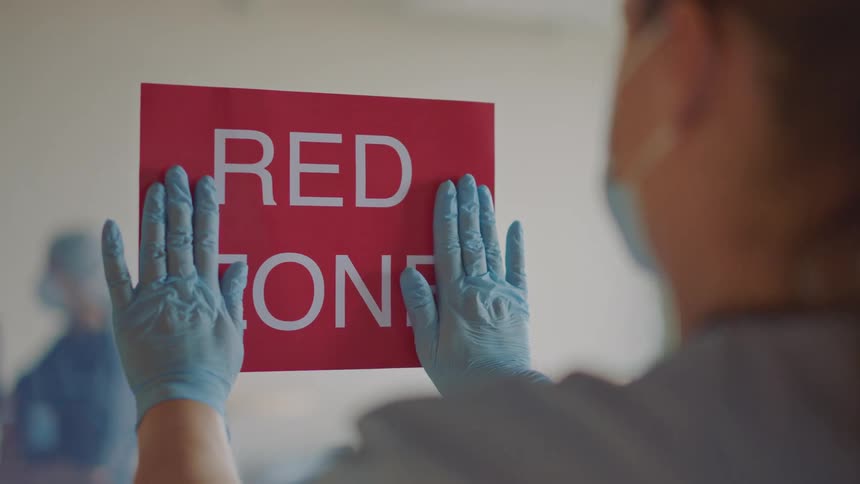 A woman hangs a warning sign on a door in a hospital