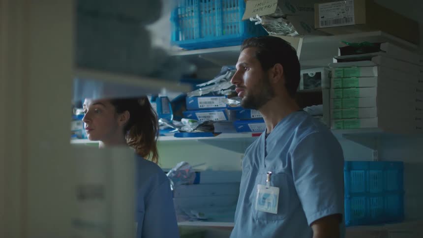 Two nurses discuss supplies while standing in medical supply closet