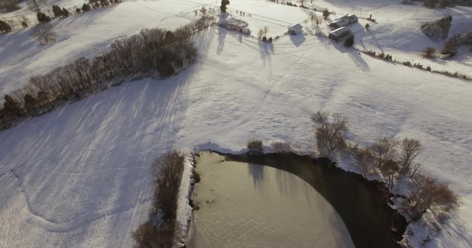 Aerial view of a snowy field and pond