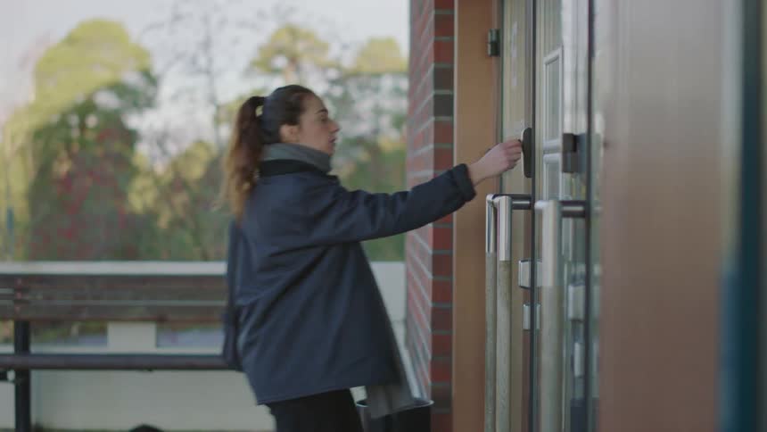 Woman opens a building door with an electronic key and enters in the morning