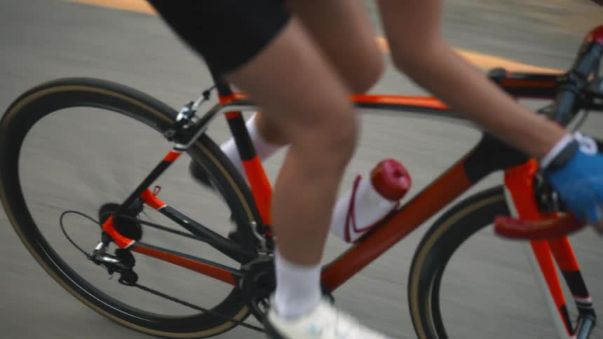 Young fit woman wearing sports clothing riding a red bicycle on a road in the countryside