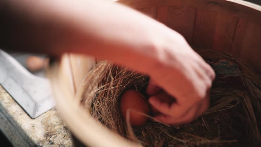 Woman takes eggs from bucket to clean in sink in the kitchen