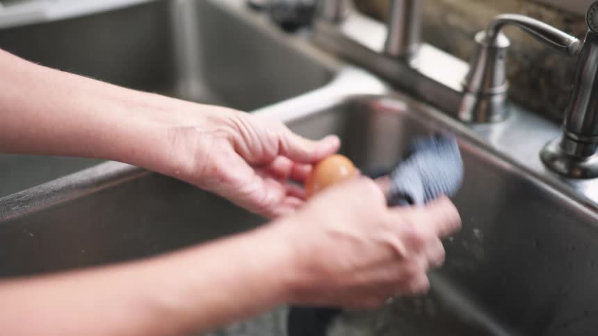 A woman washes and cleans fresh eggs in a kitchen sink