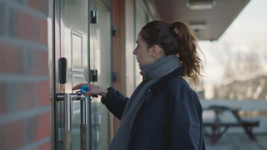 Woman with ponytail gray scarf and black coat opens clinic door