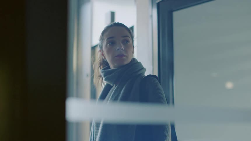Woman with ponytail gray scarf and black coat enters clinic