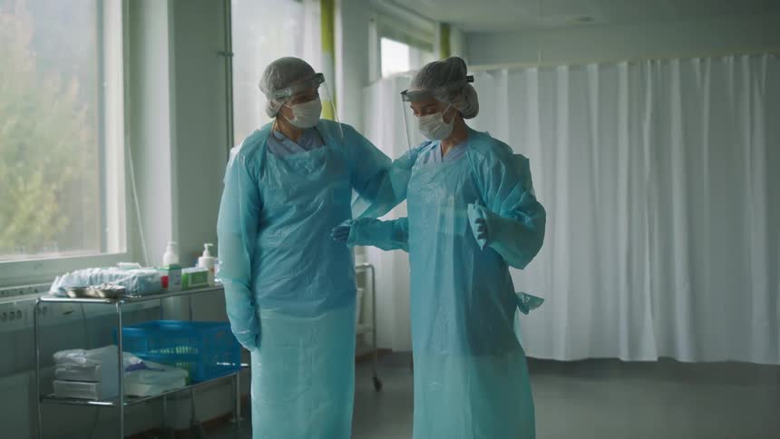Two healthcare workers are standing and talking then walk away