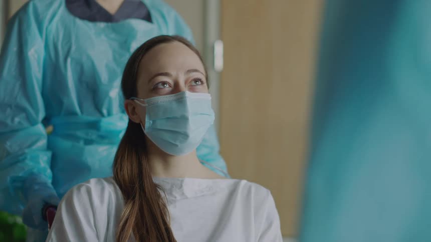 A patient waves goodbye to a nurse as shes pushed in a wheelchair